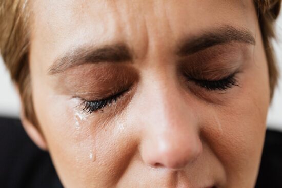 Close up of the closed eyes of a white woman, crying