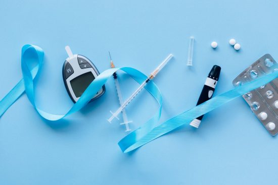 Blue background with various diabetes related items - injections, tablets and glucose monitoring device