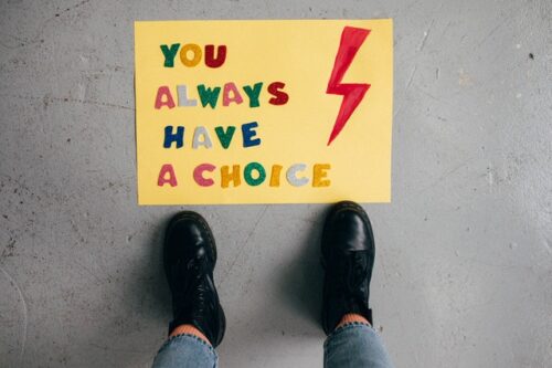 A yellow sign on the floor "You always have a choice" with a pair of shoes visible in the bottom of the shot