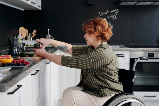 a white woman in a wheelchair chopping food at a bench
