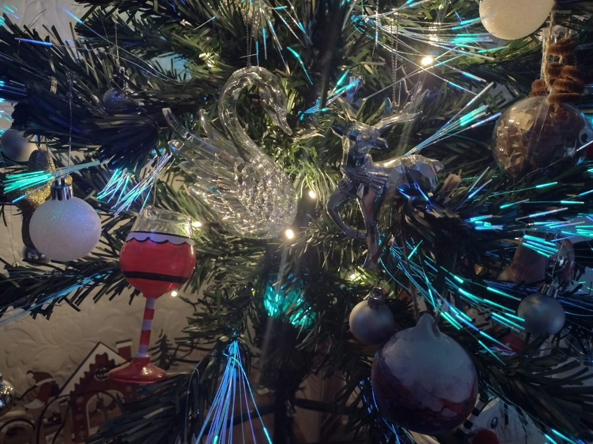a close up of two glass ornaments on a christmas tree, a swan and a stag, facig each other. The lights on the treee surrounding them are bright blue