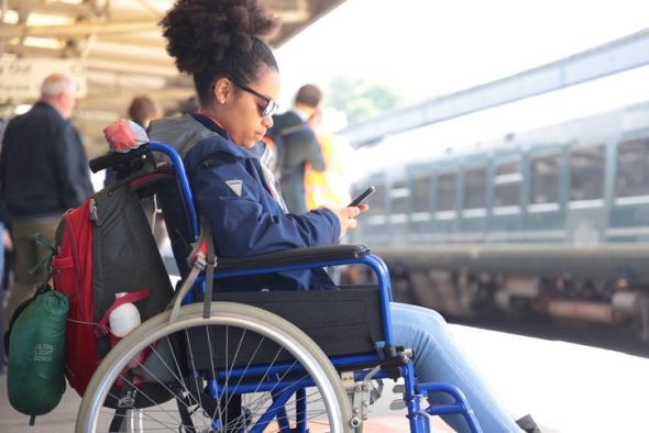 a black woman in a wheelchair waiting for a train